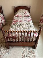 Front view of single bed showing turned spindle footboard and floral bedding