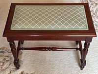 Full front view of bench on carpeted floor showing overall form and turned legs