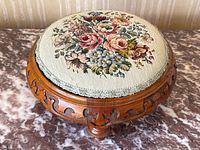 Full front-angle view of round footstool on marble surface