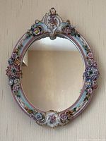Front view of oval porcelain mirror hanging on wall