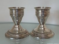 Pair of matching antique sterling silver candlesticks displayed side by side showing full front view and base details.