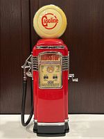Front and side view of antique style novelty gas pump radio with red and cream color, chrome accents, and 'Gasoline' top sphere.