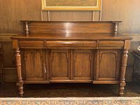 Front view of walnut sideboard showing three drawers above four cabinet doors with turned front supports