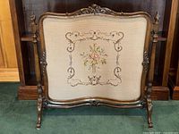 Front view of the antique wood needlepoint fire screen showing the complete frame and needlepoint panel with floral design