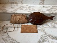 Three items on marble surface: cork shoulder purse, flat cork clutch, fish purse