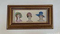 Frontal shot of the framed collection showing all three porcelain pin cushion half dolls mounted on cream fabric inside gold shadow box frame.