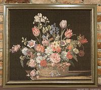 Full view of the framed floral embroidery art showing the entire piece hanging against a brick wall.