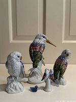 Frontal and angled views of the six porcelain bird figurines and tiny frosted blue glass bird, showing detail and size variation