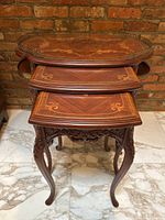 Front view of all three nested tables showing inlay tops and carved legs