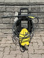 Full front view showing main unit, coiled high-pressure hose, spray gun, brush attachment and soap tube