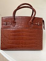 Front view of full handbag on white surface.