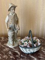 Full view of the boy figurine and flower basket placed on a marble surface against a beige textured background.