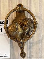Front view of entire door knocker showing kissing couple relief and ring