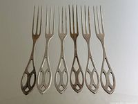 All six forks arranged upright side by side showing tines and cutout handles
