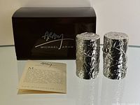 Michael Aram branded box, informational card, and salt and pepper shakers placed side by side on glass surface.