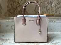 Front view of the soft blush Michael Kors tote on marble surface.