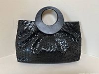 Front view of black woven leather handbag with circular handles