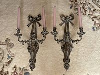 Both wall sconces laid flat on carpet showing the full pair with candles installed
