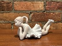 Side view of porcelain figurine of ballet dancer girl lying down.