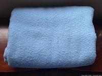 Folded queen-sized light blue wool blanket showing soft wool texture.