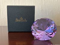 Crystal paperweight displayed standing next to a Rosenthal branded black box with gold logo, showing size and packaging.