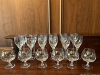 All 18 glasses arranged in two rows on wooden surface.