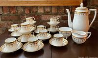Complete set of 12 espresso cups and saucers, coffee pot, creamer and sugar bowl arranged on table