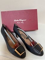 Pair of black Ferragamo pumps displayed in front of red Salvatore Ferragamo box