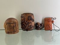 Front view of three carved wooden boxes including the mermaid and octopus motif box, mouse motif box, and the cedar box.