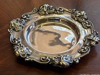 Top-down view of round sterling silver plate with ornate border design.