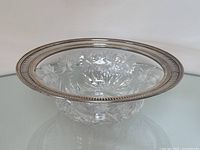 Top view of clear cut crystal bowl showing floral and butterfly cut pattern inside with detailed sterling silver rim.