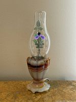 Full view of vintage Akro Agate lamp with attached Aerolux figural neon floral bulb. Shows the agate base and bulb with chimney and floral details.