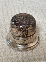 Top view of the round sterling silver ring box showing the Birks hallmark and engraved initials E M E A with tarnish and patina.