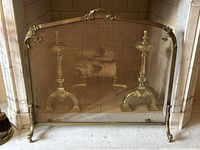 Full front view of the vintage brass floral fireplace screen sitting in front of a marble fireplace.