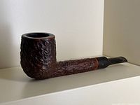 Side angle of the vintage Brigham burl walnut pipe showing the textured bowl and shank with black stem.