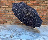 Open umbrella showing black canopy with subtle patterned design and metal frame.