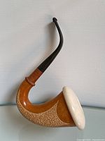 Side view of vintage calabash pipe showing the wood bowl, textured pattern, white rounded ceramic/gourd top, and curved black stem.