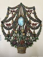 Full front view of cast iron floral wall mirror showing entire decorative piece, central oval mirror and four hooks along bottom.