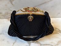 Front view of bag showing pleated fan design, twisted handle and beaded/enamel frame