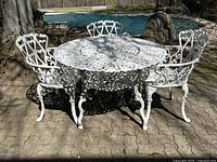 Front view of the white painted aluminum table with four matching chairs on a patio.