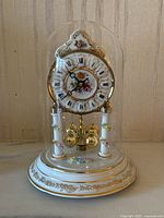 Front view showing porcelain clock face with floral design and glass dome cover