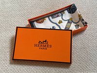 Orange Hermès box with lid removed, scarf folded inside