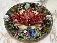 Full front view of round ceramic plate with red lobster relief and decorative ocean motifs.