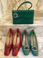 Green leather handbag by Colin Campbell with silver-tone, enamel parrot buckle. Two pairs of women's shoes: green Colin Campbell shoes with matching parrot buckles and red Proxy heels with floral embellishments.