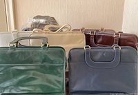 Front view showing dark green, navy, taupe, beige and brown handbags arranged in two rows