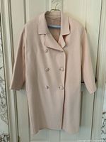 Full front view of the light pink cashmere jacket on a hanger, showing overall design and condition.