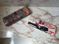 Two magazine style clutch purses laid on a marble surface showing front and side views.