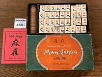 Full set including all tiles neatly laid in box compartments with scoring chips and rule book displayed beside the box.