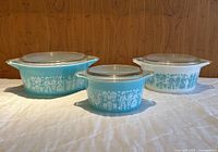 Front view of three Pyrex Amish Butterprint casserole dishes with lids arranged side by side