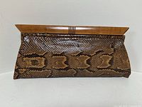 Front view of brown snakeskin clutch purse with wooden frame clasp